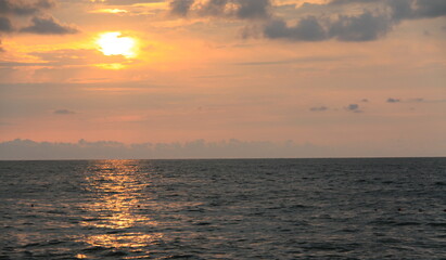 Obraz premium Golden sunset over calm ocean horizon with warm sunlight reflecting across gentle waves