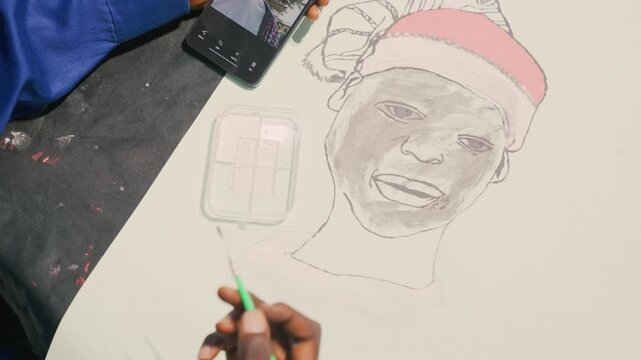 Black community artist drafting memorial painting portrait on paper, careful hand tracing tribute features of smiling black man, planning poster layout with smartphone reference, reverent atmosphere,