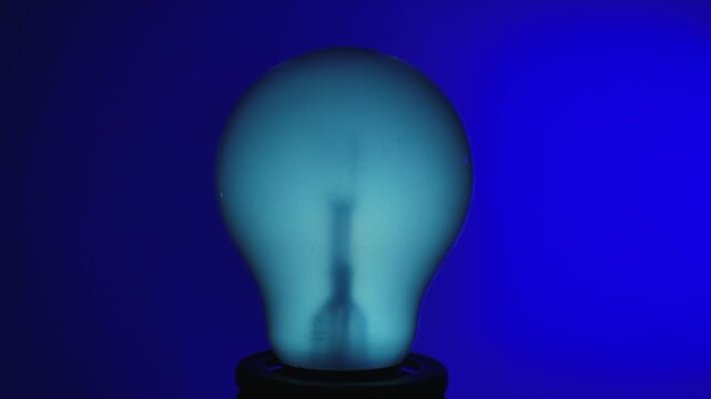 A warmly glowing light bulb that changes colors against a blue background. Captures the essence of innovation and warmth.