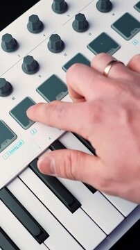 Close-up of hand with wedding ring tapping drum pads on a MIDI keyboard controller in a home studio, shallow depth of field for music production and beatmaking b-roll.