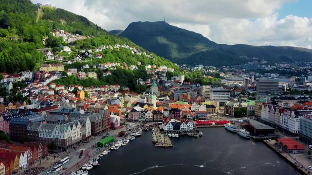 Wide aerial drone panorama over the vibrant Bergen city center and Vagen harbor. Captures the urban landscape, traditional houses, and maritime activity in western Norway on a sunny day