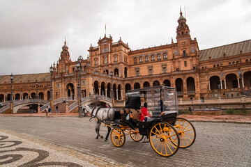 Naklejka premium Plaza de Espana, Sivilla. Historic stone building with towers and courtyard under cloudy sky