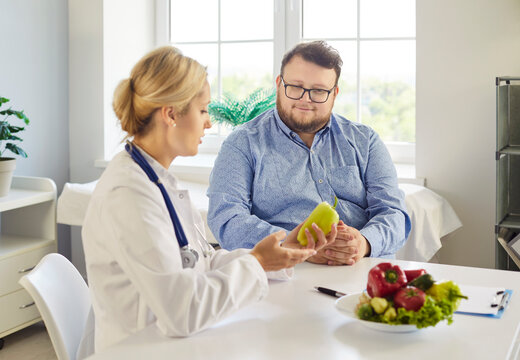 Dietitian and patient discuss nutrition and weightloss. Healthcare professional uses vegetables to explain diet choices and guide obesity care. Concept: weight management and preventive care.