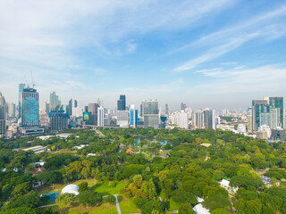Fototapeta premium Aerial view modern office building with green tropical Lumpini park forest blue sky business travel background Bangkok Thailand