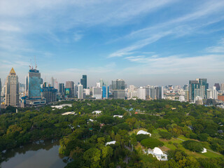 Obraz premium Aerial view modern office building with green tropical Lumpini park forest blue sky business travel background Bangkok Thailand