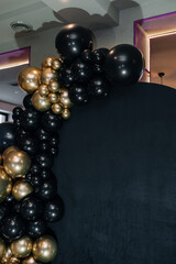 Close up of black and gold balloons on dark festive backdrop.