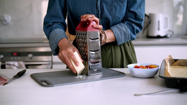 Woman Grating Cheese With A Metal Grater In The Kitchen