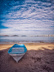 Fototapeta premium A small blue boat is sitting on the beach