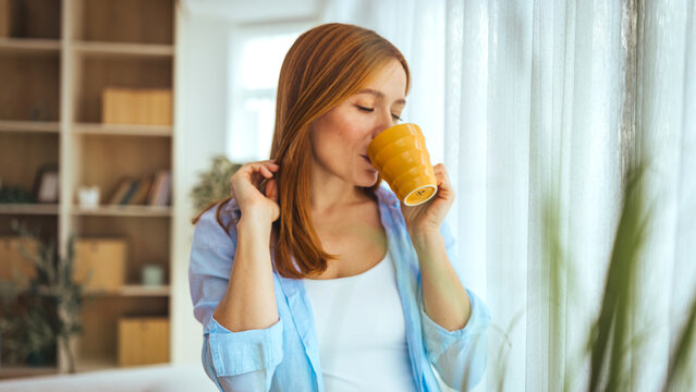 Relaxed Woman Drinking Coffee At Home In Morning Light With Yellow Mug Near Window