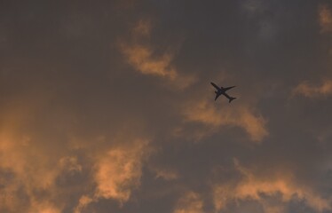 Obraz premium plane flying throgh white and orange cloud floating on sky in twilight sunset sky at evening