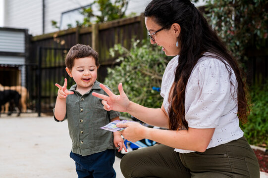 Toddler boy counting with mum using their fingers outdoors