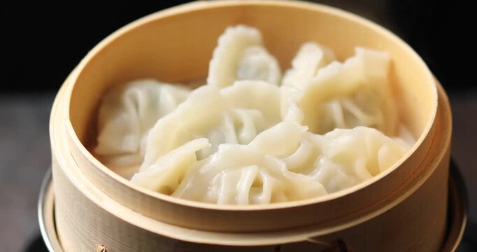 Chinese dumplings with meat and vegetables in a bamboo steamer.	