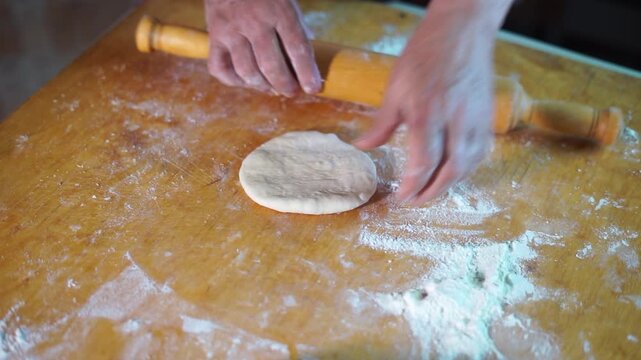 Women's hands make pasty dough. Woman rolls out a flatbread