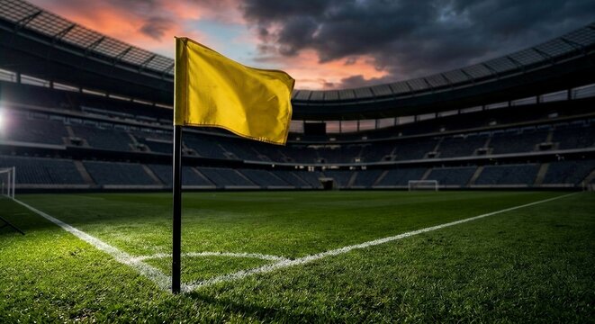 Dramatic wide-angle shot of a yellow corner flag on a pristine green soccer pitch inside an empty grand stadium under a moody sunset sky.