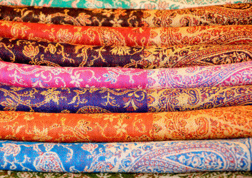 Variety of colorful shawls with floral patterns at street market stall display. Oriental Fashion background..