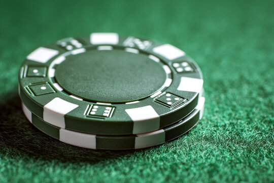 Stack of green and white casino poker chips on felt table