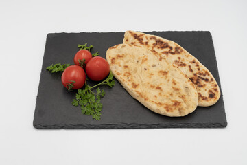 Warm traditional flatbread with toasted crust served with fresh tomatoes, herbs and thick tomato sauce. Rustic food presentation.