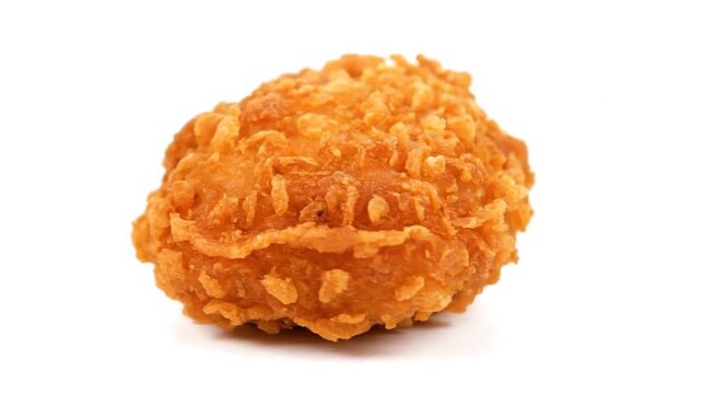 A close-up view of a crispy fried chicken nugget on a clean white surface from a front viewpoint showing the texture and detail