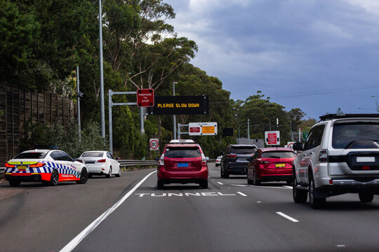 car pulled over on roadside by police with traffic passing and sign saying please slow down