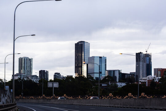 Light posts and skyscrapers rising above road and trees in city