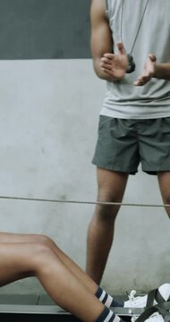 Woman, exercise and coach in gym with rowing machine, endurance and high five for fitness success. Happy, personal trainer and people in health club with ergometer, celebration and workout milestone.
