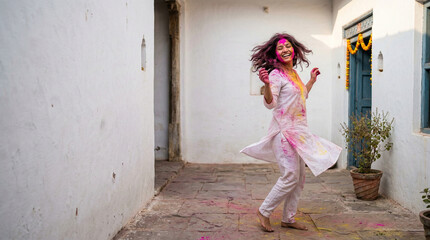 Naklejka premium Happy Indian woman dancing with colorful powder during Holi festival