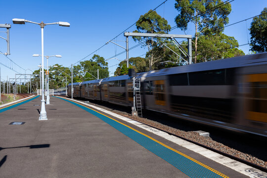 Motion blur of passenger train speeding past platform of Narwee station in Sydney suburb 