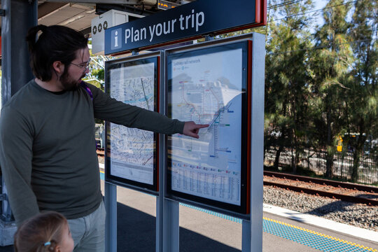 Plan your trip sign showing railway lines in Sydney with man pointing to location