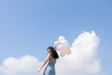 A Chinese girl playing with balloons under a blue sky and white clouds   © mei