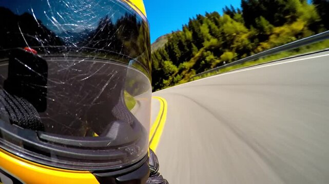 Motorcycle rider navigates a winding mountain road on a sunny day with a scratched visor