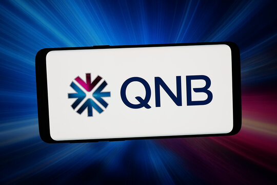 Stuttgart, Germany - 02-25-2026: In this photo illustration, the logo of company Qatar National Bank (QNB Group) is displayed on a smartphone in front of abstract background on computer screen.