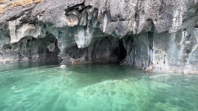 Slow cinematic footage capturing the Marble Caves on Lago General Carrera in Patagonia, Chile. The camera gently moves along sculpted marble rock formations and small natural caves .