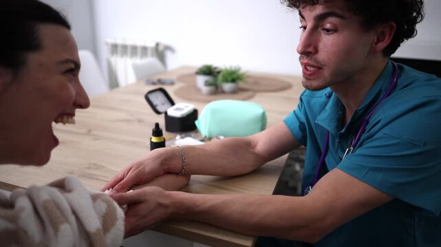 Male nurse or doctor using lancet on a woman's finger to check blood sugar level with a glucometer during a home visit, demonstrating diabetes management and patient care