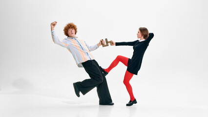 Stylish business duo pulling puzzle piece in dynamic pose. Concept of negotiation tension,...