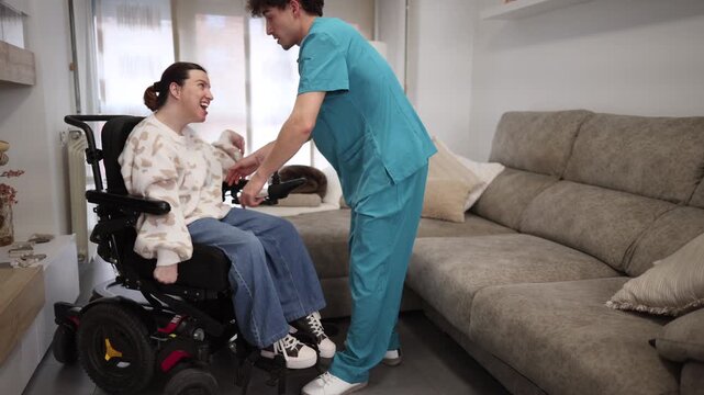 Dedicated male caregiver gently transferring smiling woman from her electric wheelchair to a sofa in a cozy living room, showing professional, compassionate in home support and mobility assistance