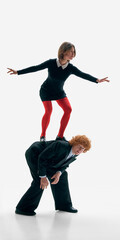 Woman standing on mans back balancing with arms extended on white studio background. Concept of...