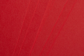 Fototapeta premium Top view of stacked bright red textured paper sheets,Close-up abstract background of multiple layers of vibrant red premium paper with a fine grainy texture, arranged in a fan-like overlapping pattern