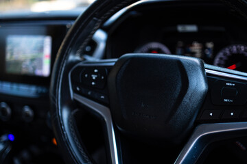 Obraz premium Modern Car Interior with Leather Steering Wheel and Digital Dashboard Display,Close-up shot of a modern vehicle's interior focusing on the black leather steering wheel with multi-function control.