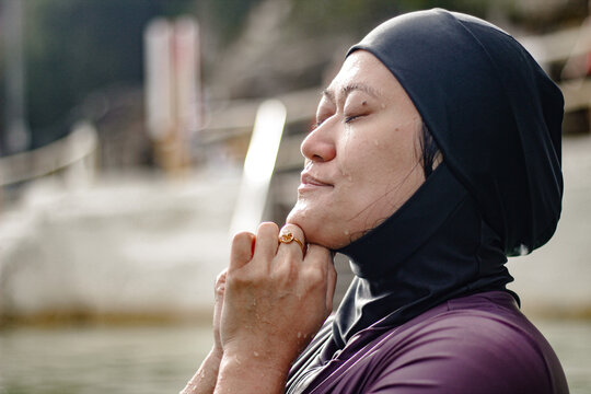 Hmong-American lifting head up with eyes closed and hands clasps together under the chin