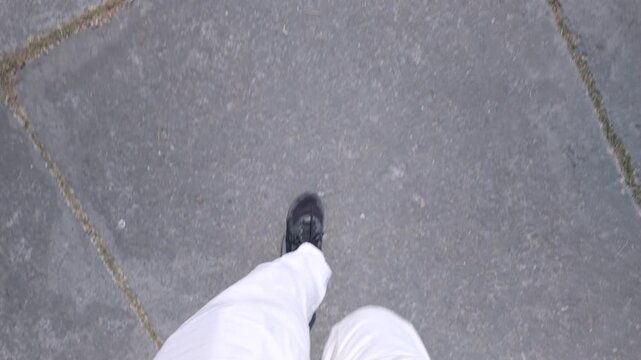 Top Down View of a Person Walking in White Pants and Black Shoes on a Sunny Day