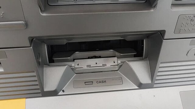 A hand take Rupiahs banknotes in ATM cash dispenser. Withdrawal, payment transaction of cash from bank terminal.