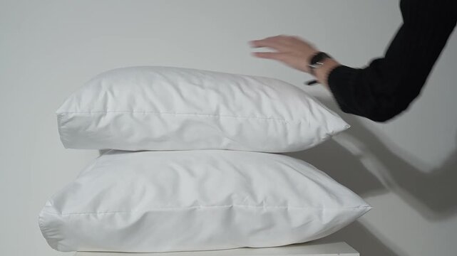white pillows on the bed, female hands rearranging the bedclothes
