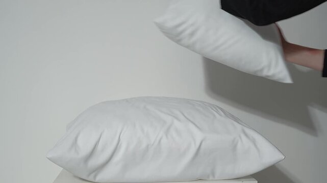 white pillows on the bed, female hands rearranging the bedclothes