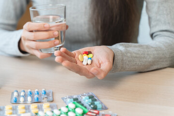 Healthcare Harmony: Close-Up Hands Holding Medication and Water Glass for Optimal Wellness,...