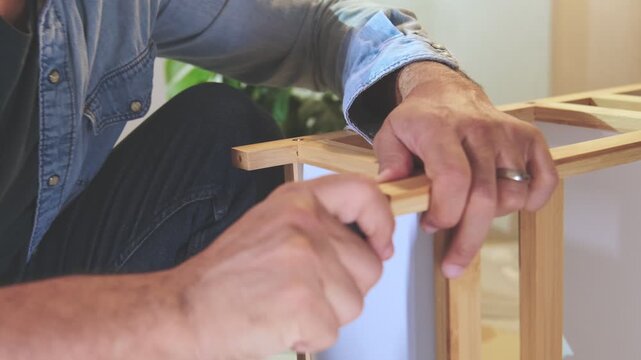 Man opening a cardboard box with furniture parts and assembly instructions