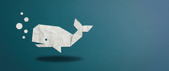 Minimalist paper origami whale swimming in a deep blue sea concept for creativity and conservation.