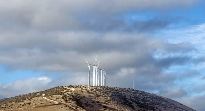 Row of wind turbines on a hill in an empty landscape of Soria province, Central Spain, on a partly overcast winter day
