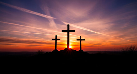 Three crosses silhouetted on a hill at a vibrant sunset