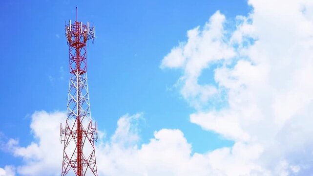 A telecommunication tower reaching towards a bright blue sky with fluffy clouds. This structure enables crucial communications