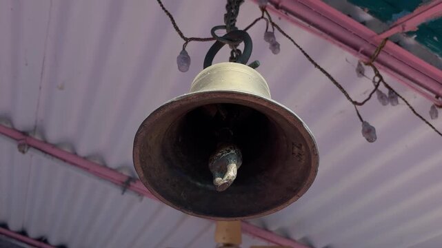 Close view of an old metal bell hanging inside a traditional Indian temple